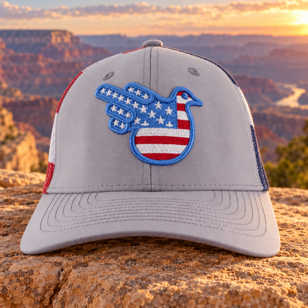 The Stars & Stripes American Bird Trucker, Gray, front on sandstone with a canyon background.