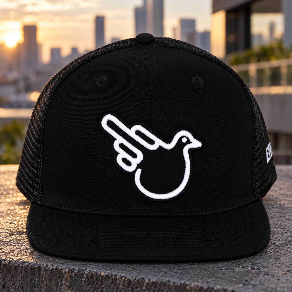 Black flat-bill trucker with raised white Double Bird on a concrete terrace.